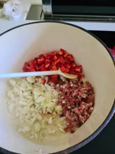 Zwiebel wird mit Paprika und Speck in Kochtopf angebraten