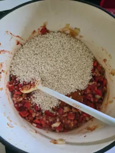 Reis wird zu Paprika in Kochtopf gegeben