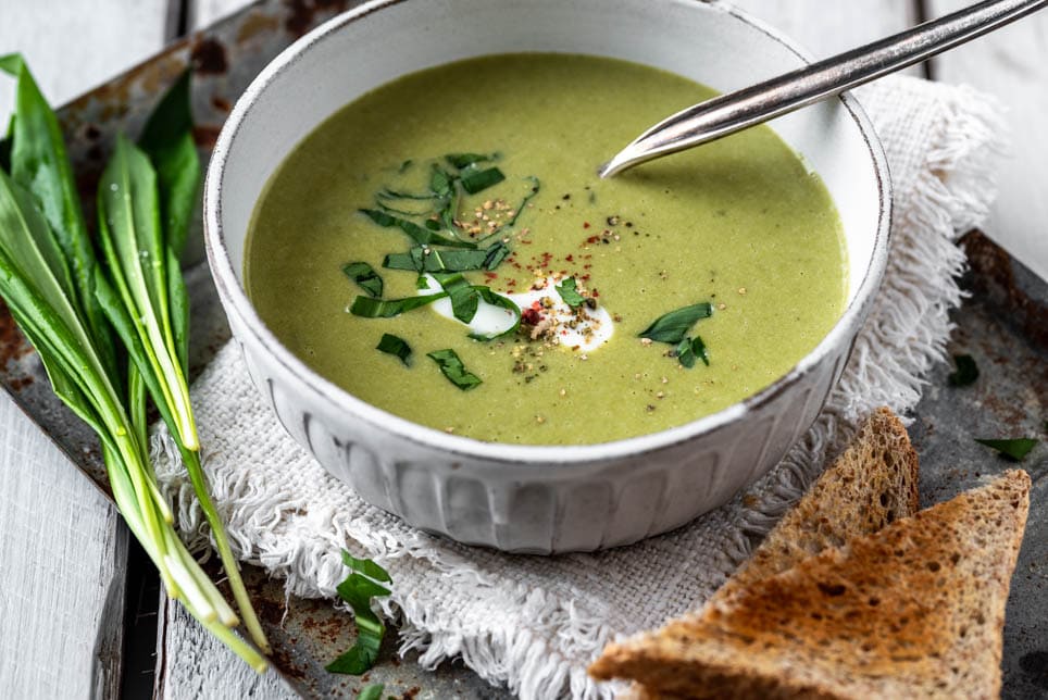 Cremige Bärlauchsuppe mit Kartoffeln in Schale, garniert mit frischem Bärlauch und Gewürzen