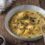 Eine Schüssel mit Kartoffelsuppe und einer Serviette auf Holzuntergrund