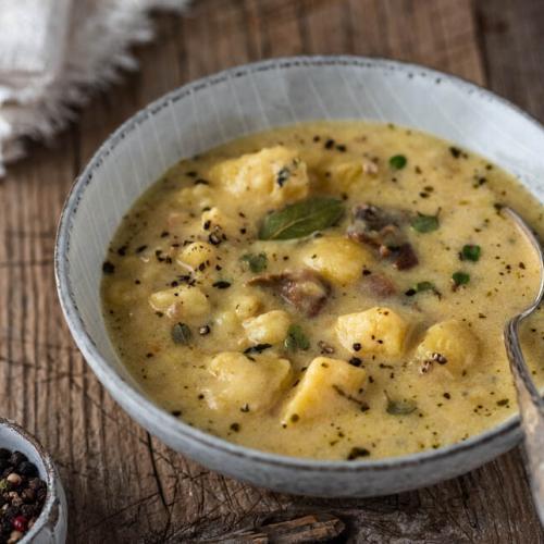 Eine Schüssel mit Kartoffelsuppe und einer Serviette auf Holzuntergrund