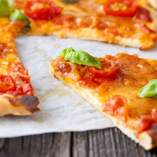 Ein Stück Pizza Margherita auf Backpapier