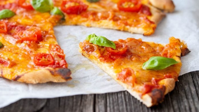 Ein Stück Pizza Margherita auf Backpapier