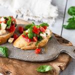 2 Stück Bruschetta mit Tomaten auf einem Brettchen