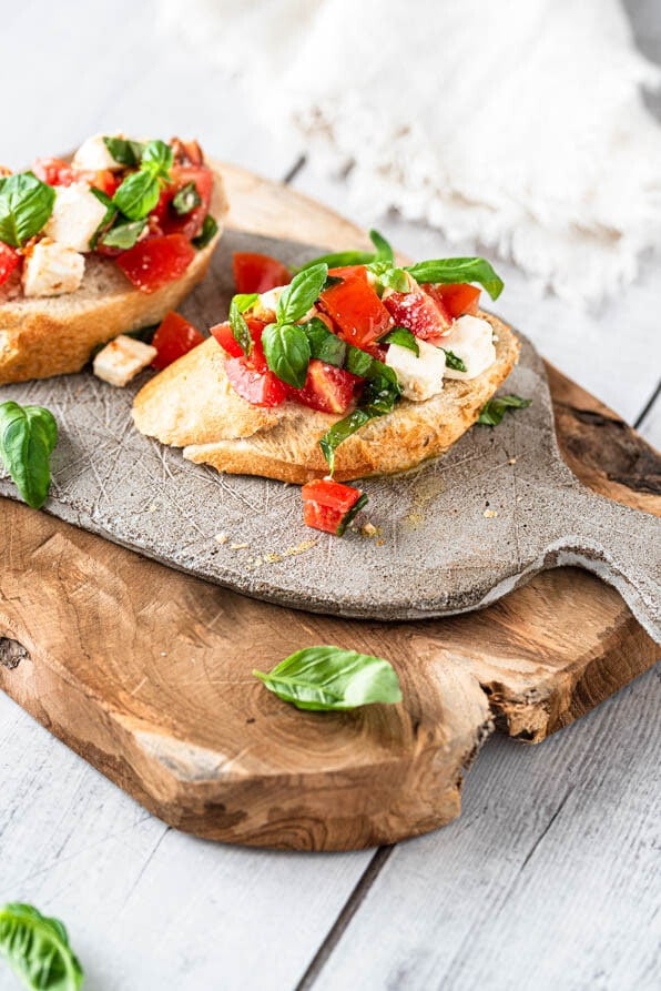 2 Stück Bruschetta mit Tomaten auf einem Brettchen