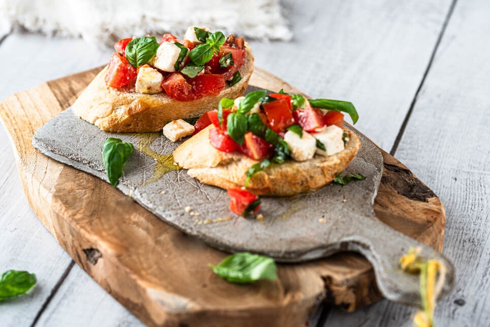 2 Stück Bruschetta mit Tomaten auf einem Brettchen