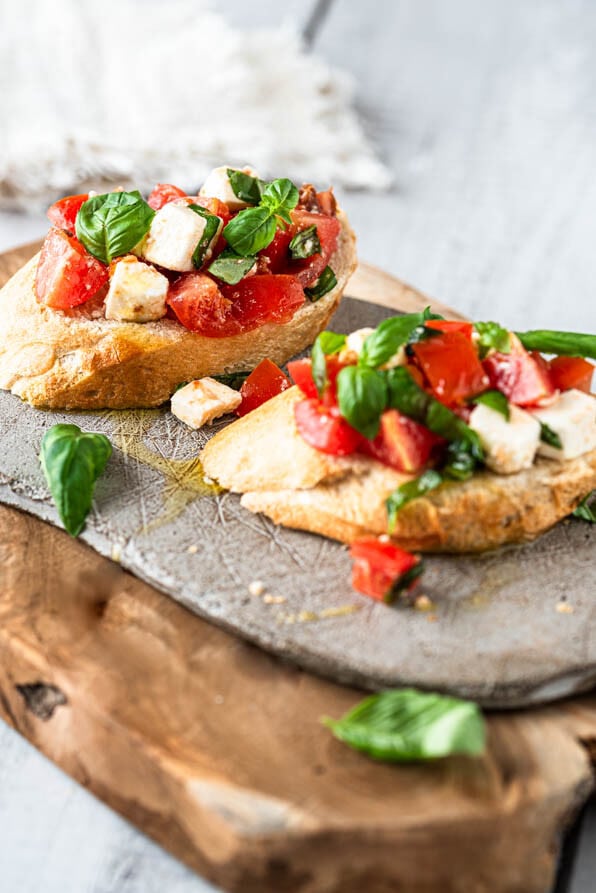 2 Stück Bruschetta mit Tomaten auf einem Brettchen