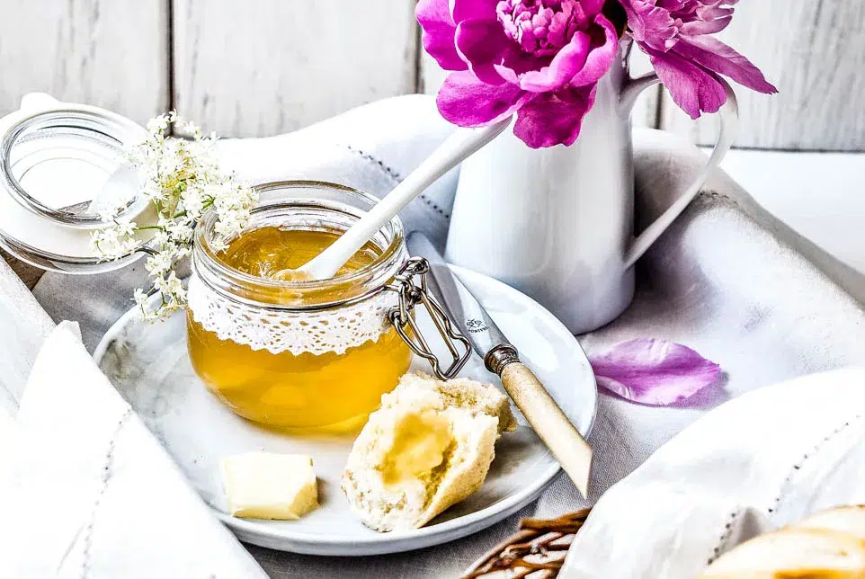 Ein Frühstückstablett mit Holunderblütengelee, Gebäck und Blumen