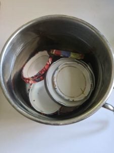 Deckel von Marmeladegläsern in Kochtopf mit Wasser bedeckt