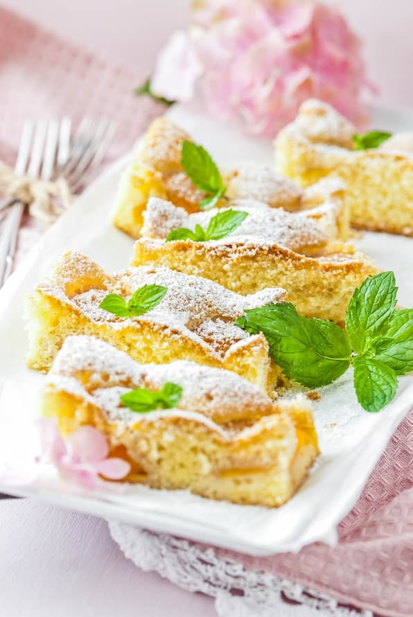 einige Stücke Aprikosenkuchen liegen auf einem Teller und sind mit Pfefferminze garniert