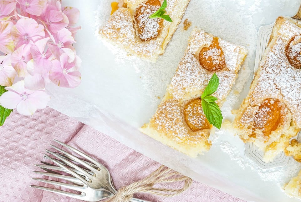 einige Stücke Aprikosenkuchen liegen auf einem Teller und sind mit Pfefferminze garniert