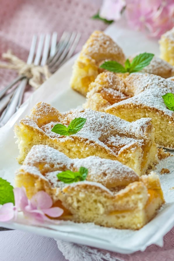 einige Stücke Aprikosenkuchen liegen auf einem Teller und sind mit Pfefferminze garniert