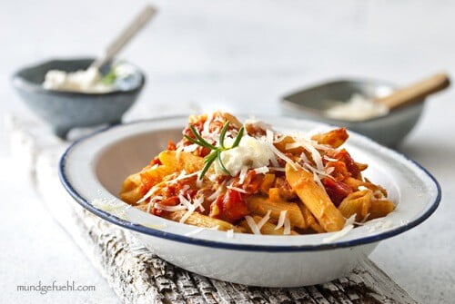 A plate of penne with ricotta and tomato sauce topped with rosemary and parmesan