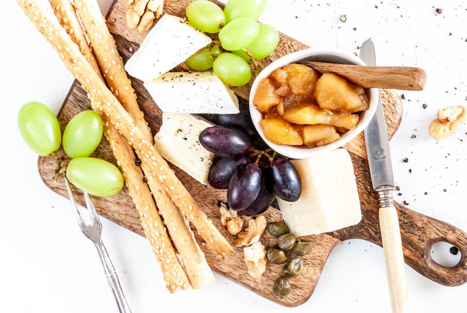 Käseplatte garniert mit Apfelchutney, Weintrauben und Grissini