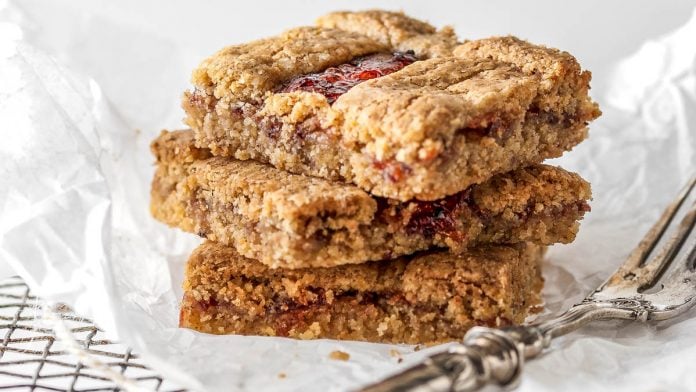 Drei Stück Linzer Schnitten liegen aufeinander auf einem Gitter
