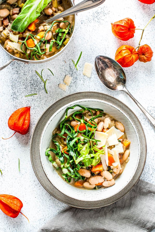 Bohnensuppe in einem Teller steht vor einem Topf mit Suppe.