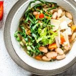 Bohnensuppe in einem Teller steht vor einem Topf mit Suppe.