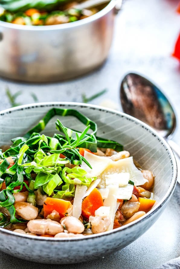 Bohnensuppe in einem Teller steht vor einem Topf mit Suppe.
