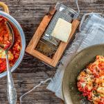 Mit Tomaten und Mozzarella überbackenes Huhn wird von feuerfester Form auf Teller angerichtet