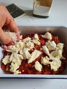 Parmesan wird in Auflaufform gestreut