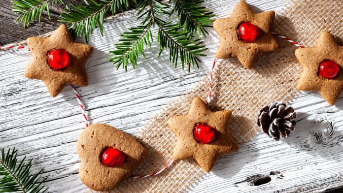 lebkuchenkekse-mit-kandierten-kirschen Lebkuchenkekse liegen neben Tannenzapfen auf einem Brett
