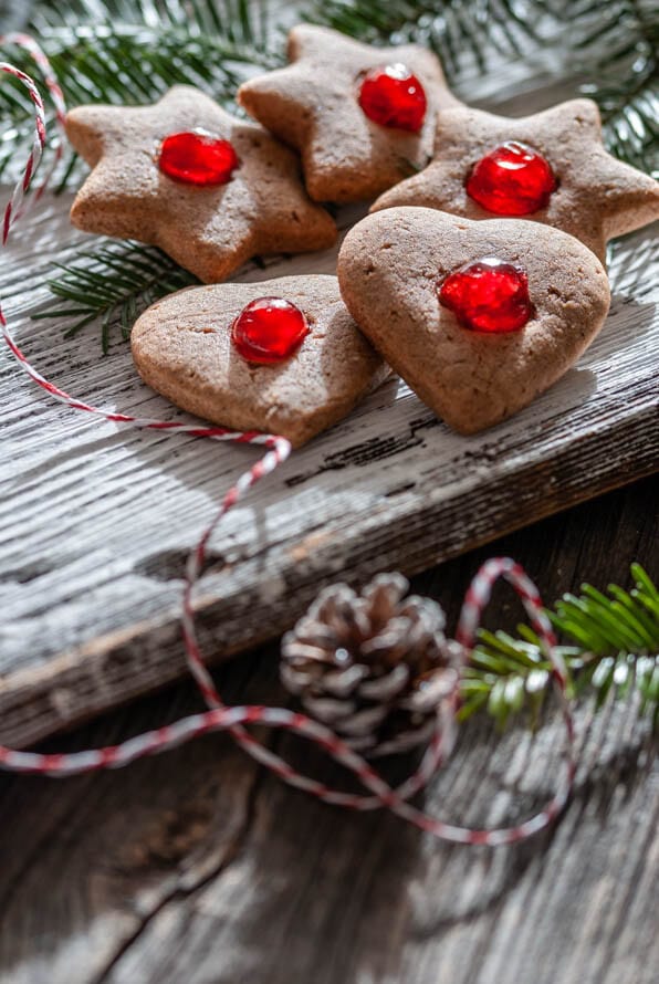 Lebkuchenkekse liegen neben Tannenzapfen auf einem Brett