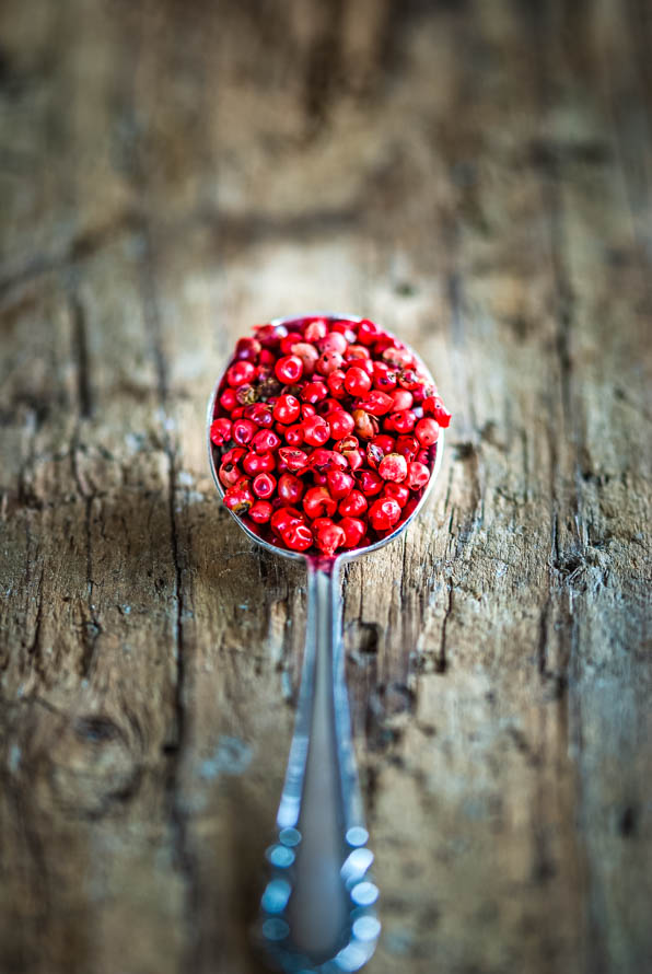 rosa Beeren auf einem Löffel, der auf Holzbrett liegt