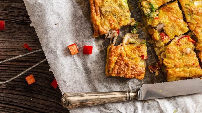 in Stücke geschnittene Frittata liegt auf Backpapier und daneben ein Messer