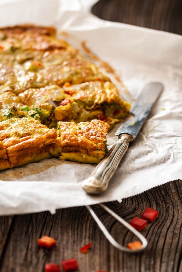 in Stücke geschnittene Frittata liegt auf Backpapier und daneben ein Messer