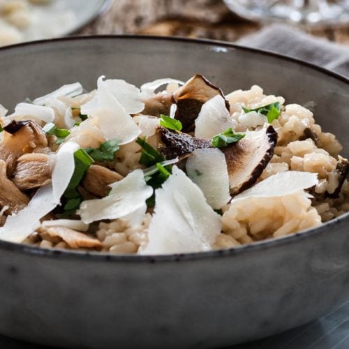 Steinpilzrisotto steht mit einem Glas Wein auf dem Tisch