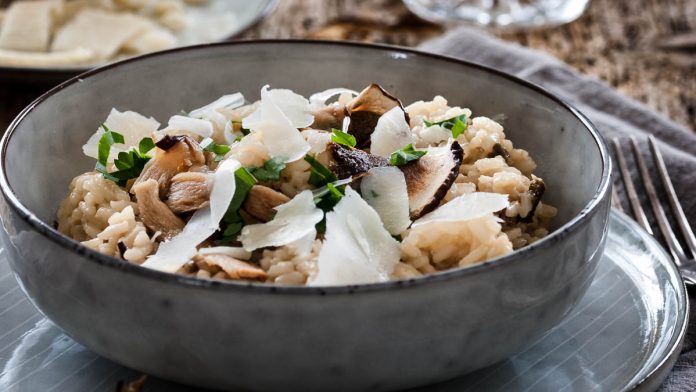 risotto-mit-getrockneten-steinpilzen Steinpilzrisotto steht mit einem Glas Wein auf dem Tisch