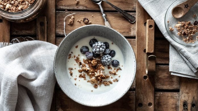 Eine Schüssel mit Granola, Brombeeren und Joghurt steht am Tisch