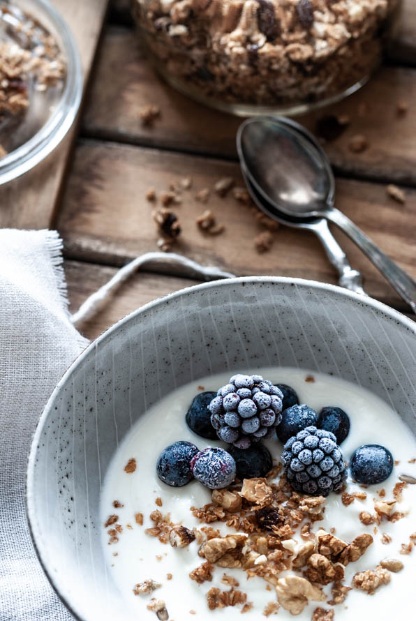 Eine Schüssel mit Granola, Brombeeren und Joghurt steht am Tisch