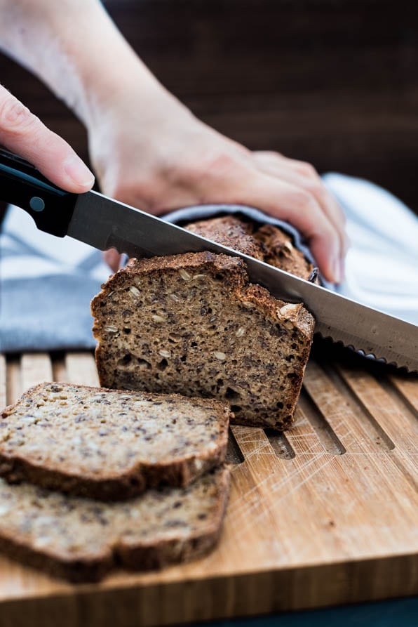 Hand schneidet Brot mit Brotmesser