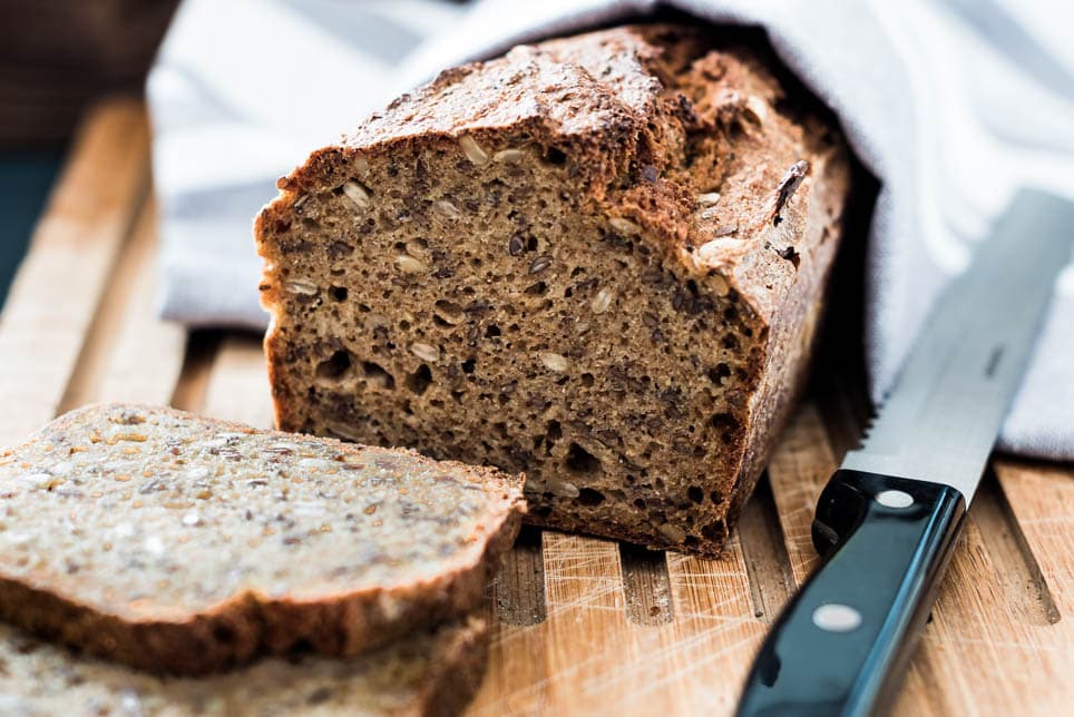 Brot liegt mit einem Messer auf einem Holzbrett