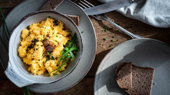 Rührei mit Trüffel und Brot auf einem Holztisch