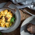 Rührei mit Trüffel und Brot auf einem Holztisch