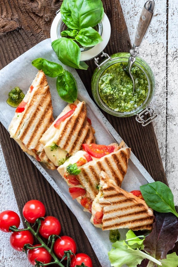 Toast mit Tomaten, Mozzarella und Basilikumpesto ist in kleinen Dreiecken angerichtet