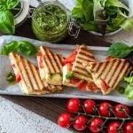 Toast mit Tomaten, Mozzarella und Basilikumpesto ist in kleinen Dreiecken angerichtet