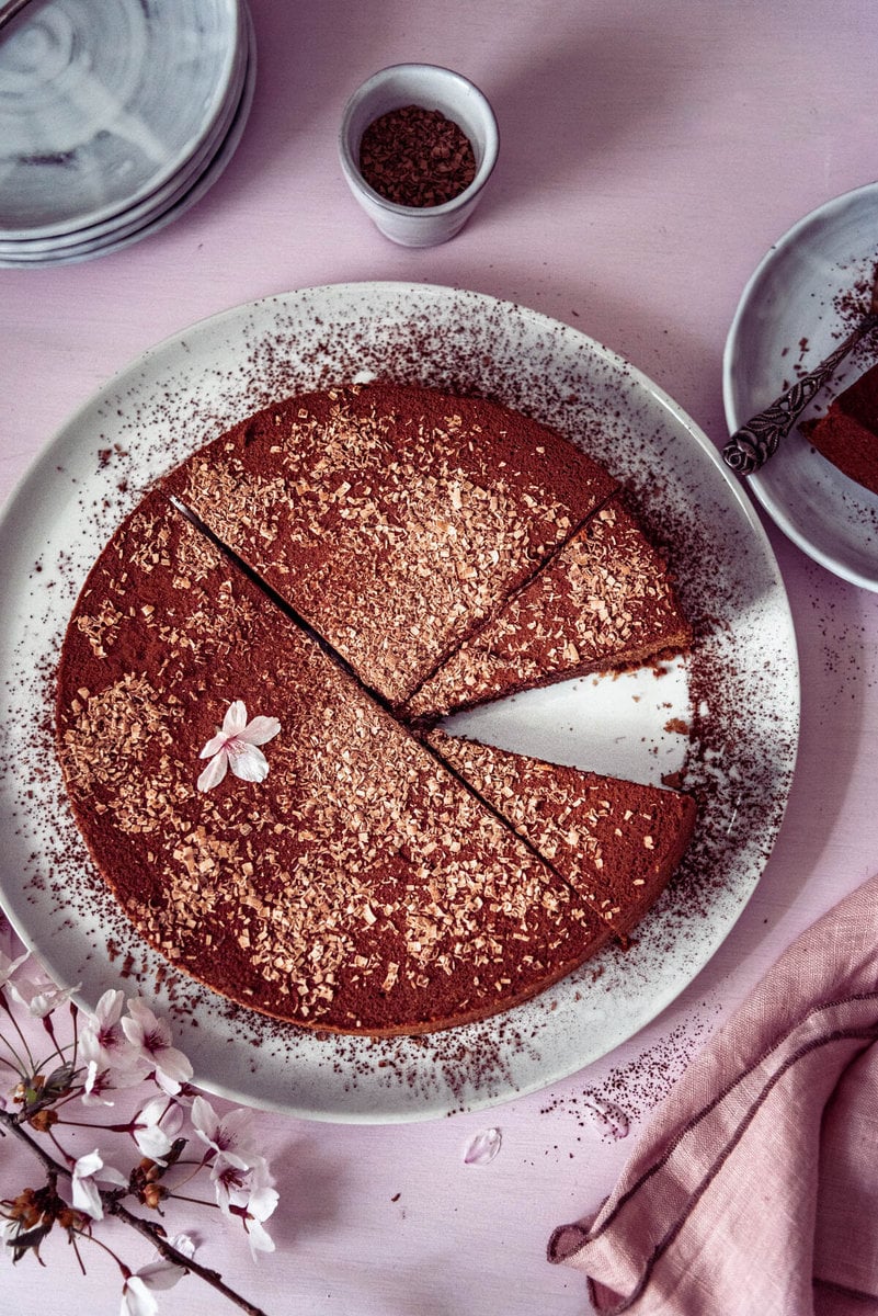 Eine Schokotorte garniert mit Blüten steht auf einem Tortenteller
