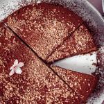 Eine Schokotorte garniert mit Blüten steht auf einem Tortenteller