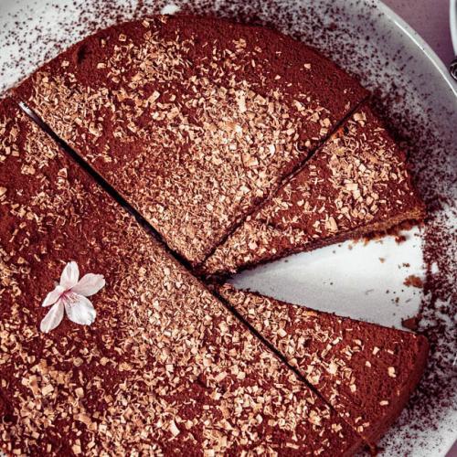 Eine Schokotorte garniert mit Blüten steht auf einem Tortenteller