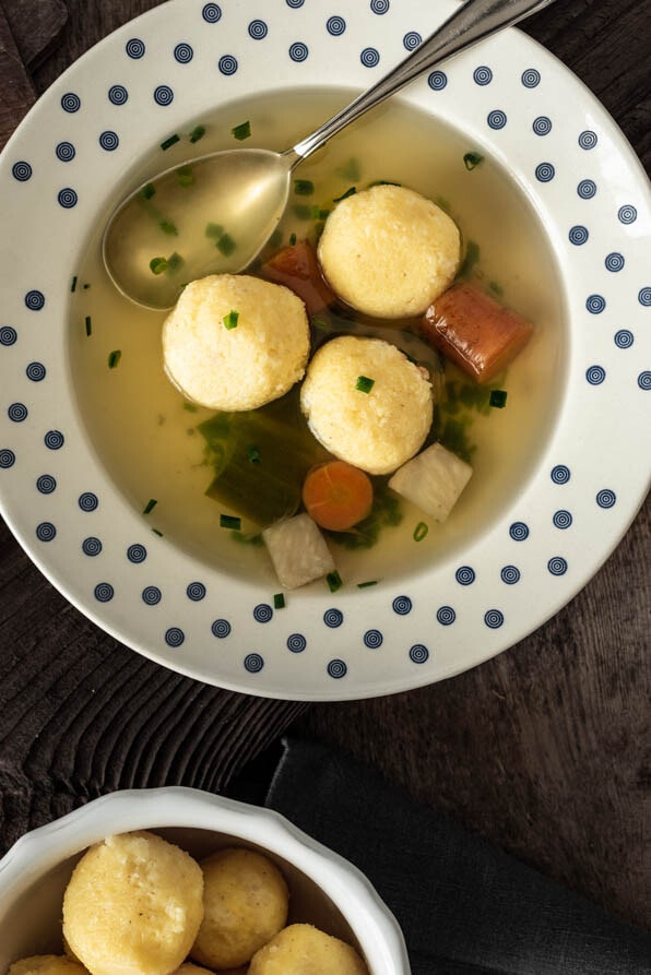 Suppenteller mit Grießnockerlsuppe und einem Löffel