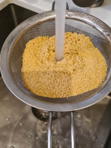 Hirse in Sieb unter fließendem Wasser