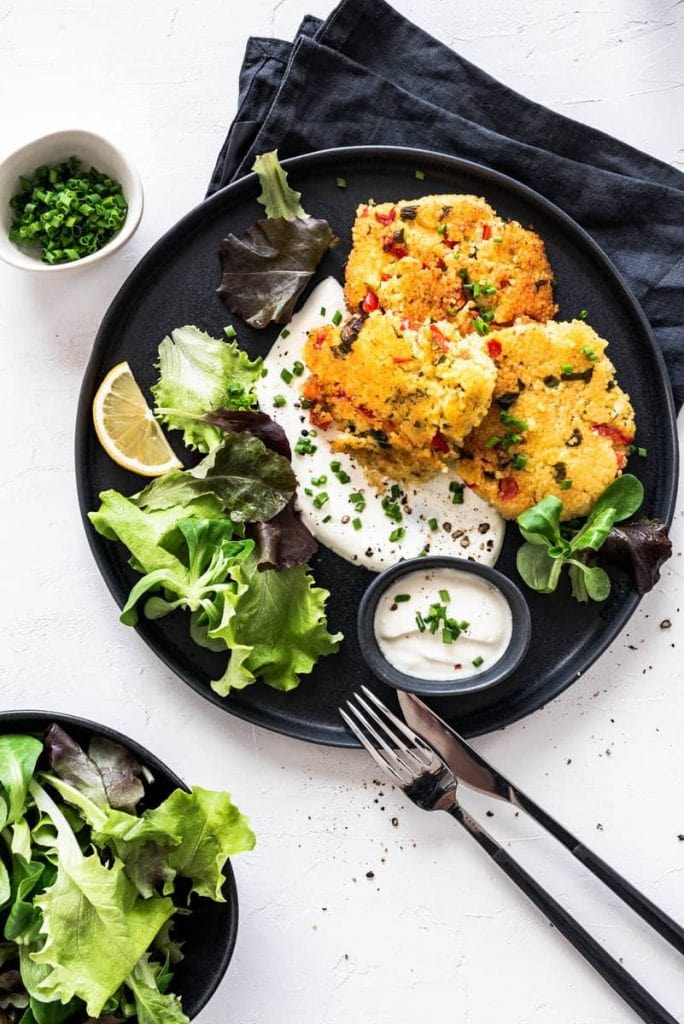 Hirselaibchen mit Salat und Dip auf einem schwarzen Teller