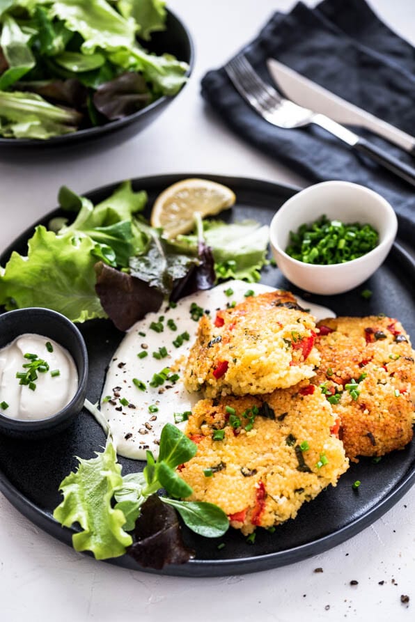 Hirselaibchen mit Salat und Dip auf einem Teller mit Serviette und Besteck