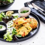 Knusprige Hirselaibchen mit Salat und Dip auf einem schwarzen Teller