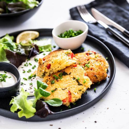 Knusprige Hirselaibchen mit Salat und Dip auf einem schwarzen Teller