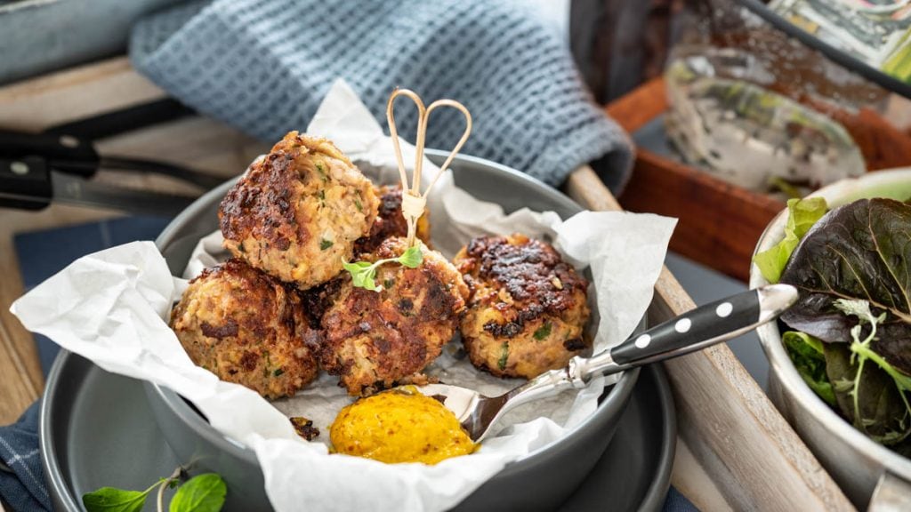 auf einem Tablett steht ein Teller mit Fleischbällchen und Besteck