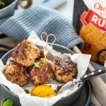 auf einem Tablett steht ein Teller mit Fleischbällchen und Besteck